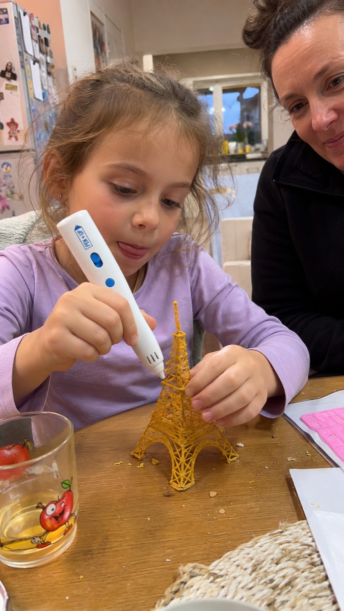 A child proudly holds the Pen'Up 3D pen and a model just made with it